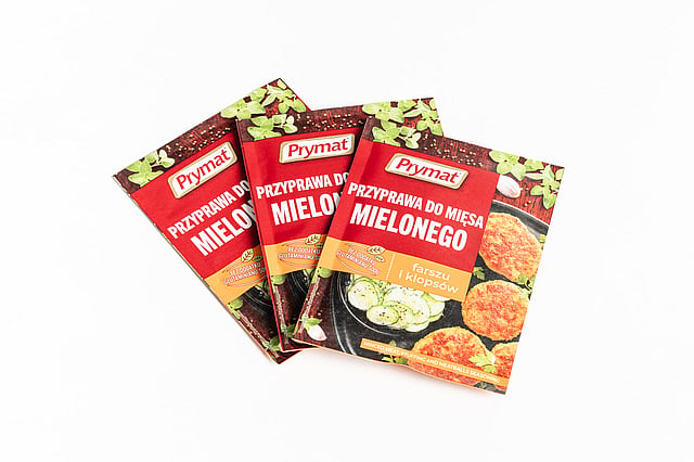 A set of three overlapping Prymat seasoning packets displayed on a white background. The packets are labelled ‘Przyprawa do mięsa mielonego’ and feature images of cooked meat patties and sliced cucumbers. The packaging is predominantly red with green herb motifs at the top